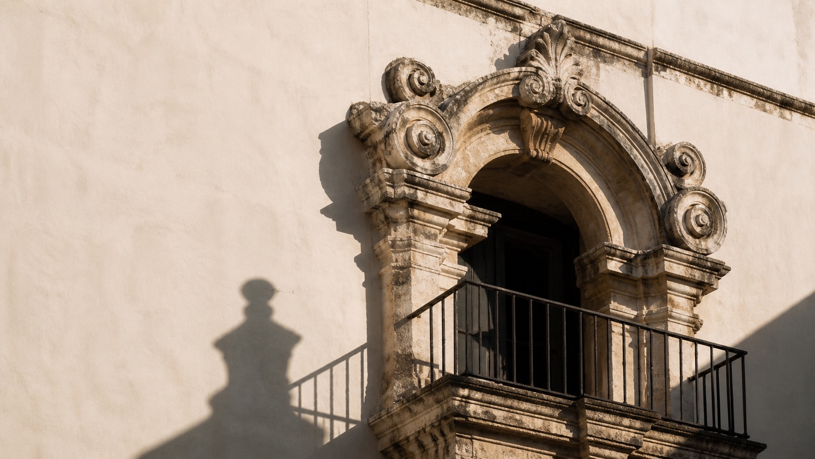 Dettaglio architettonico barocco del centro storico di Grottaglie: balcone in pietra con ombra radente sulla parete bianca